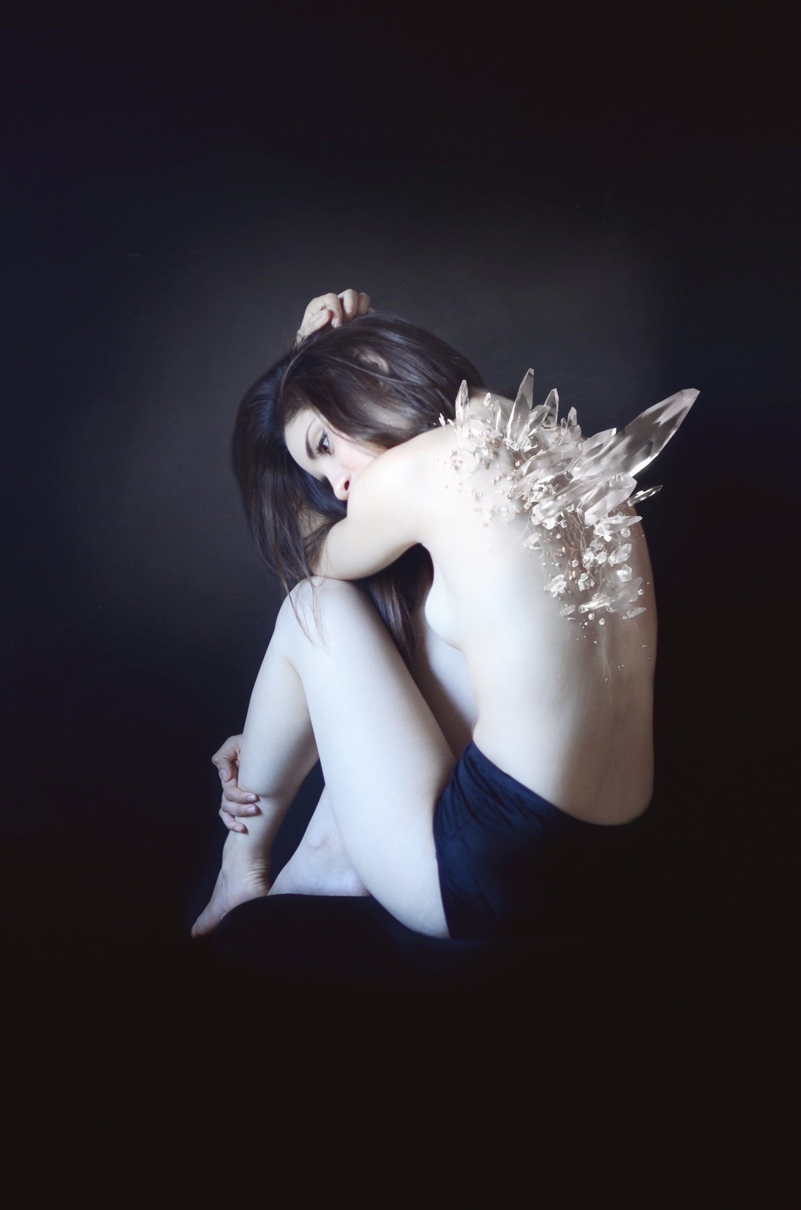 Mariana Esquivel's ethereal portrait captures a female figure with shimmering crystals emerging from her back set against a dark moody backdrop.
